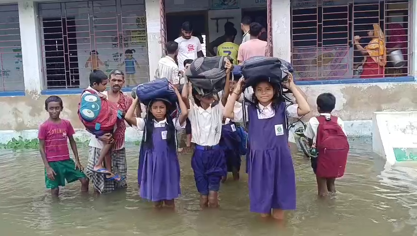 School Field or Pond—A Dilemma! Students Wading Through Water Up to Their Knees and Waists, Parents Carrying Children